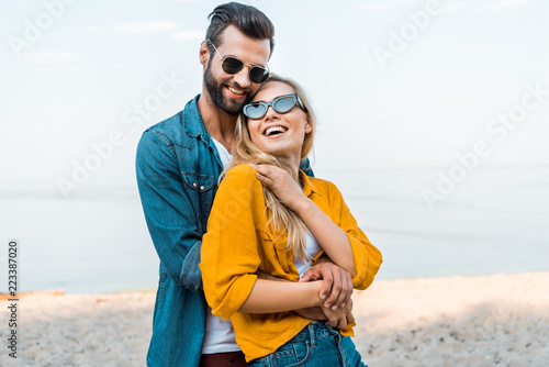 boyfriend hugging laughing girlfriend on beach