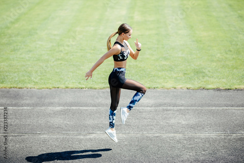 Side view of confident young sportswoman dressed in sportswear warming up at the stadium outdoorsh