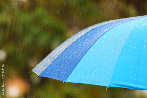 Bright umbrella under rain on street, closeup