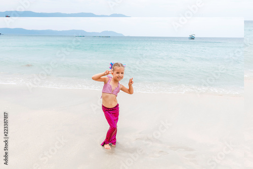 Little beautiful girl dressed in swimsuit as a mermaid stay on the seashore