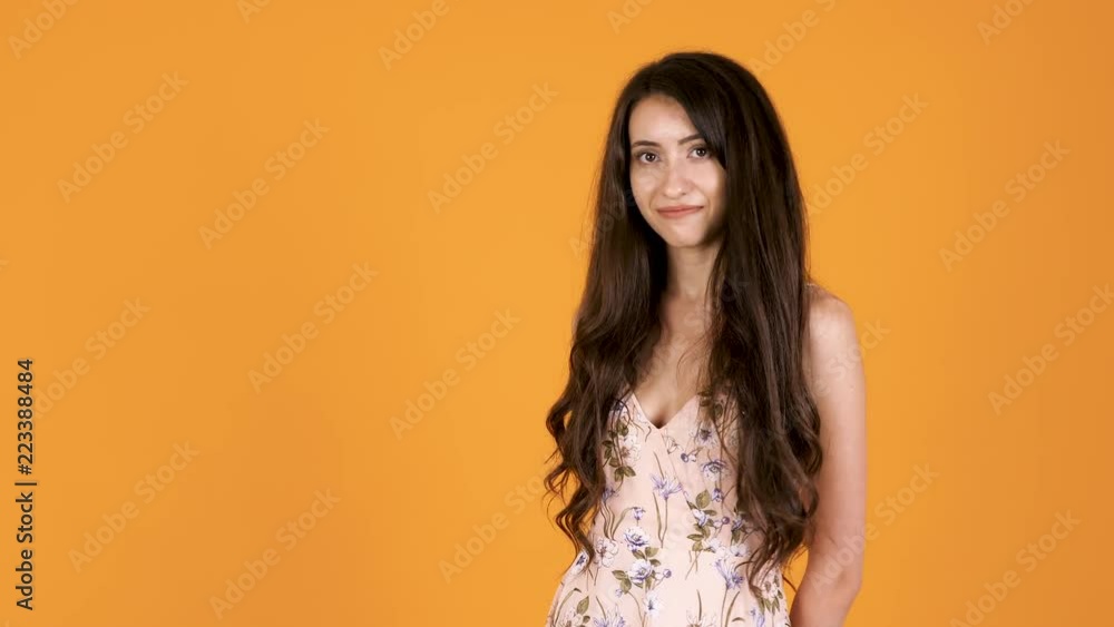 Beautiful shy girl looking at the camera isolated on orange yellow background Beautiful shy girl looking at the camera isolated on orange yellow background