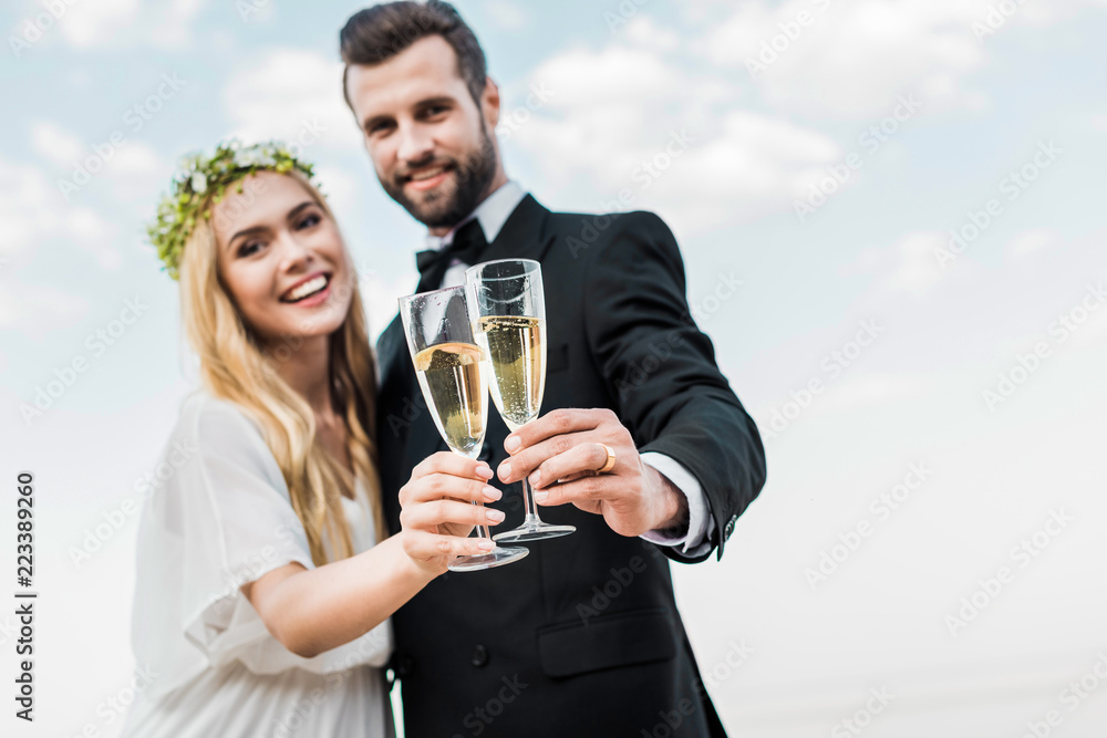selective focus of wedding couple clinking with glasses of champagne on beach selective focus of wedding couple clinking with glasses of champagne on beach