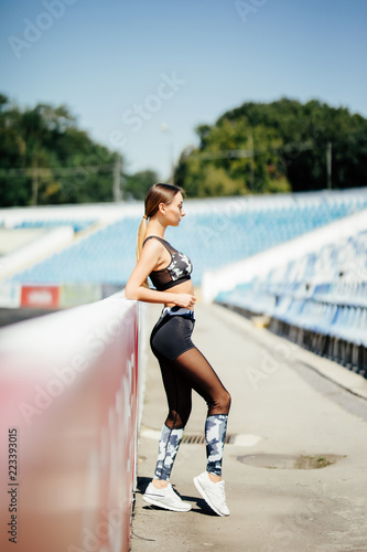 Portrait of fitness woman doing warm up exercises at stadium