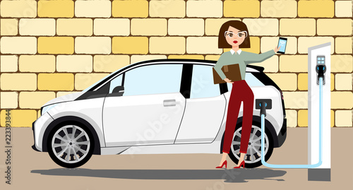 Woman charges an electric car at a charging station for electric vehicles. Woman next to the electric car.