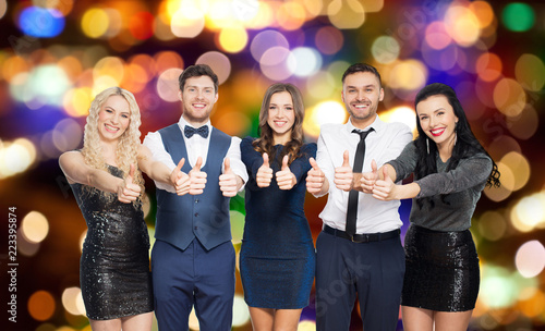 celebration, people and holiday style concept - happy friends in party clothes showing thumbs up over lights background