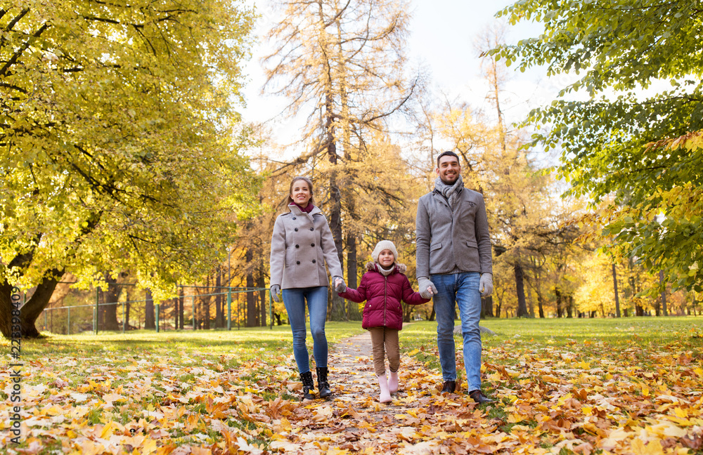 family, season and people concept - happy mother, father and little daughter walking at autumn park