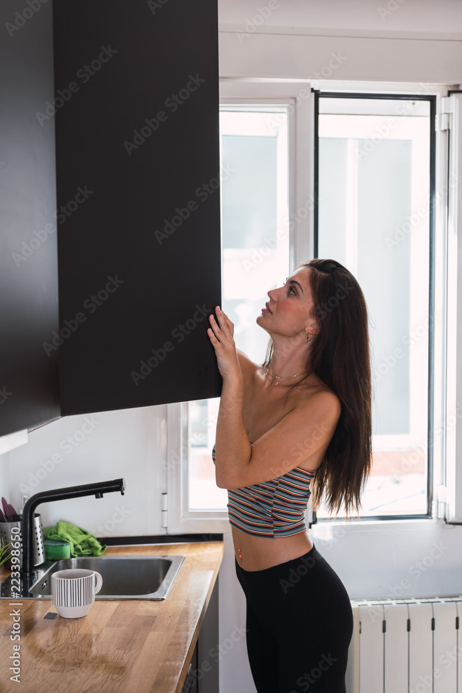 Young woman looking into opened cupboard Young woman looking into opened cupboard