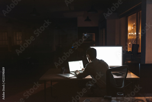 Businessman working overtime at his desk late at night photo