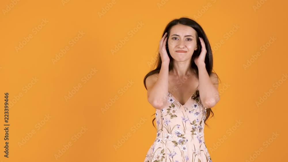 Woman in summer dress saying NO with gestures while looking at the camera. Unsatisfied girl isolated on orange yellow background in studio Woman in summer dress saying NO with gestures while looking at the camera. Unsatisfied girl isolated on orange yellow background in studio