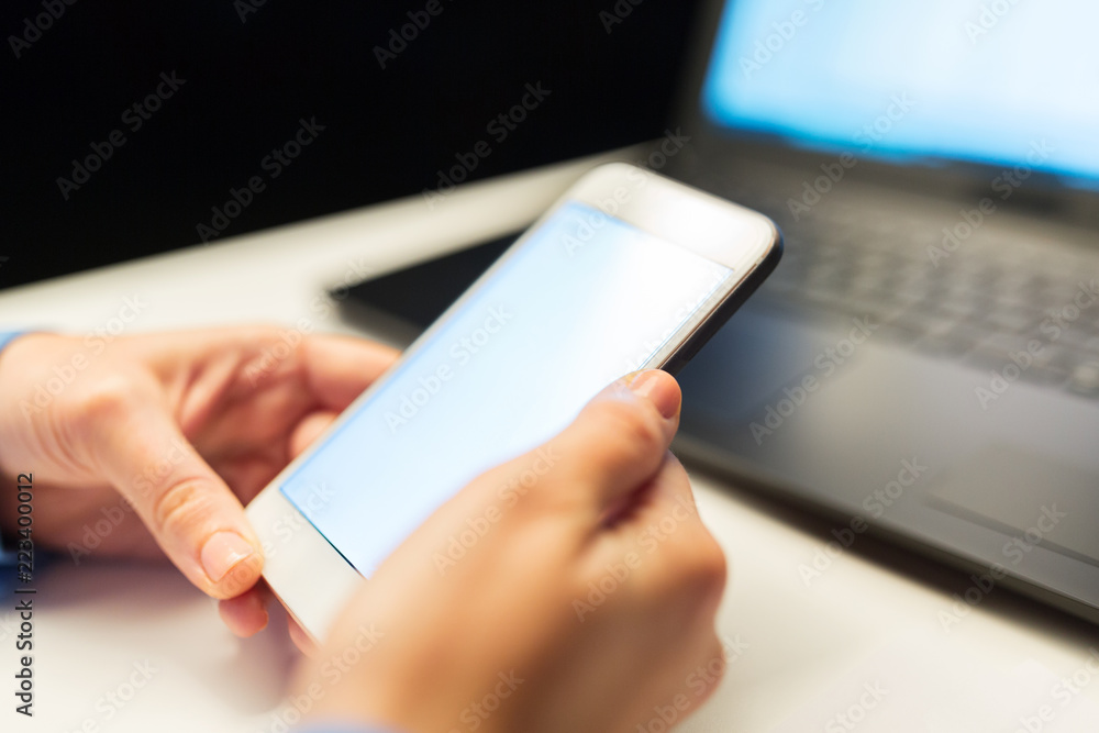 business, deadline and technology concept - close up of businesswoman hands with smartphone and laptop computer working at night office business, deadline and technology concept - close up of businesswoman hands with smartphone and laptop computer working at night office