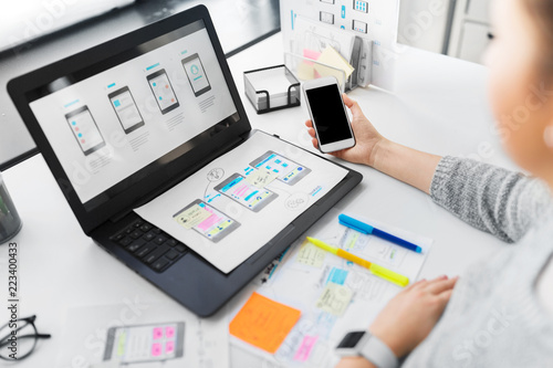 app design, technology and business people concept - web designer or developer with smartphone and laptop computer working on user interface at office