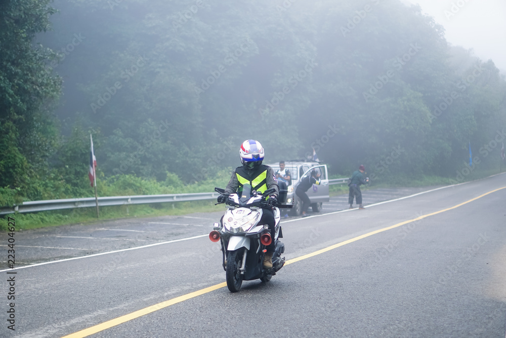 Thai police are driving a motorbike. Up to Doi Inthanon, Chiang Mai - Thailand. On the road in a covered with thick fog and freezing.