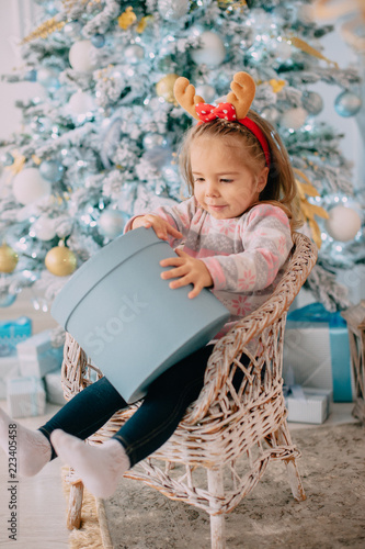 girl unpacks gift on background of Christmas tree © MZaitsev