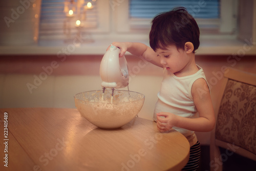 boy prepaing dough with mixer in the kitchen photo