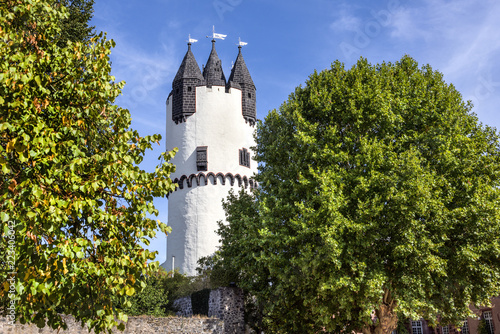 Germany, Rhine-Main area, Hanau, Steinheim: Famous white donjon tower in the green castle park of the German town with flags, old vintage city wall, trees and blue sky - concept travel architecture
