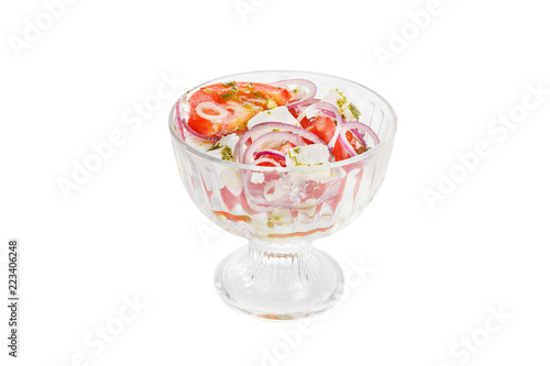 Salad of vegetables in a glass bowl of vegetables, tomatoes, onions, feta, cheese, salakis, pesto sauce, basil, spices, white isolated background Side view. For the menu, restaurant, bar cafe