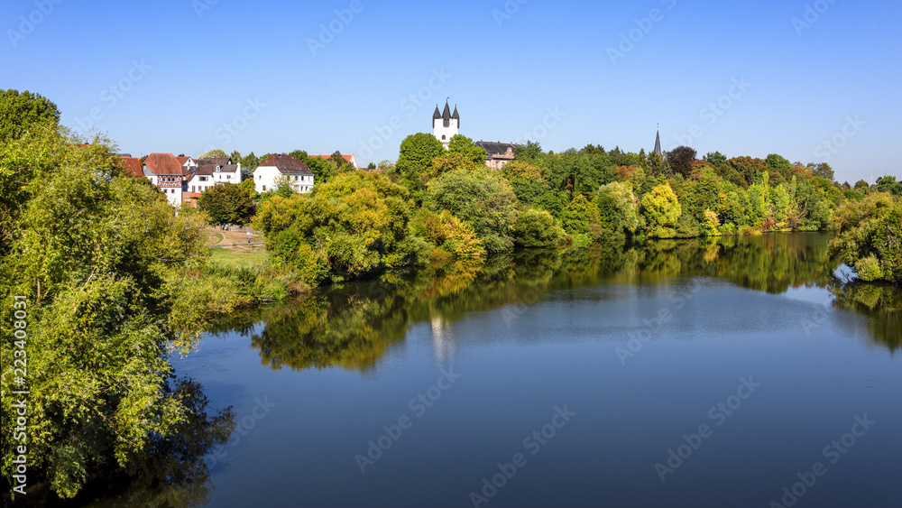 Germany, Rhine Main area, Hanau, Steinheim: Reflection of skyline in calm Main river with green castle park, famous donjon, white tower, roof top of mansion, museum, trees and blue sky in background.