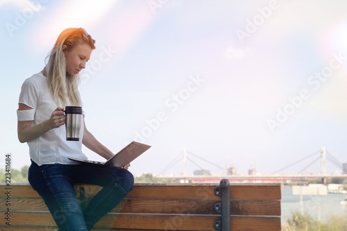 Freedom concept, choose perfect workplace for yourself. Young business woman using laptop outdoors and dkinking coffee