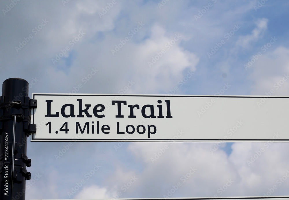 The lake trail sign in the park with a sky background. The lake trail sign in the park with a sky background.