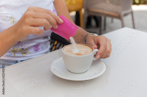 Woman hand adding sugar in coffee