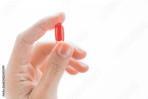 Female hand holding red tablet with two fingers close-up isolated on a white background