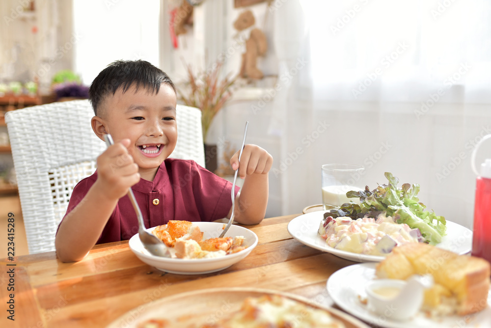 Boy is eating breakfast Little boy sitting at the table, eating breakfast Boy is eating breakfast Little boy sitting at the table, eating breakfast