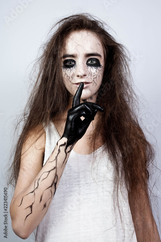 crazy girl with disheveled hair, black eyes and veins shows her finger shh. Halloween concept. photo