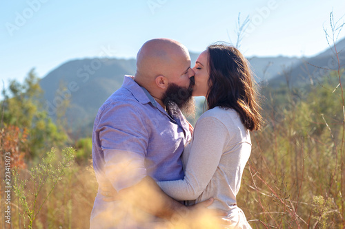 Close up of couple kissing in grass field overlooking mountains
