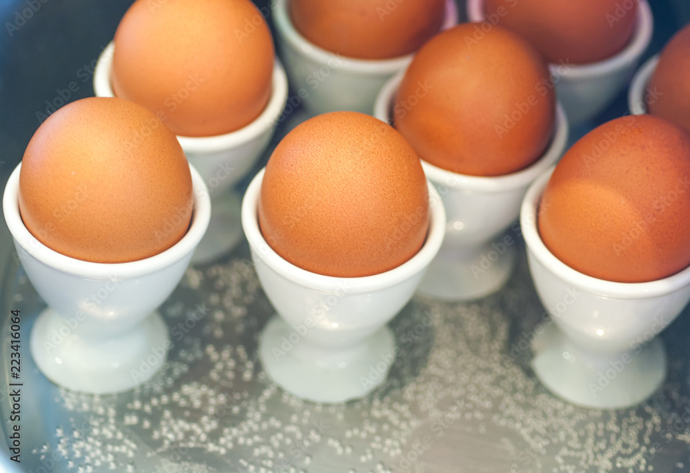 Egg cups with natural brown eggs in a boiler Egg cups with natural brown eggs in a boiler