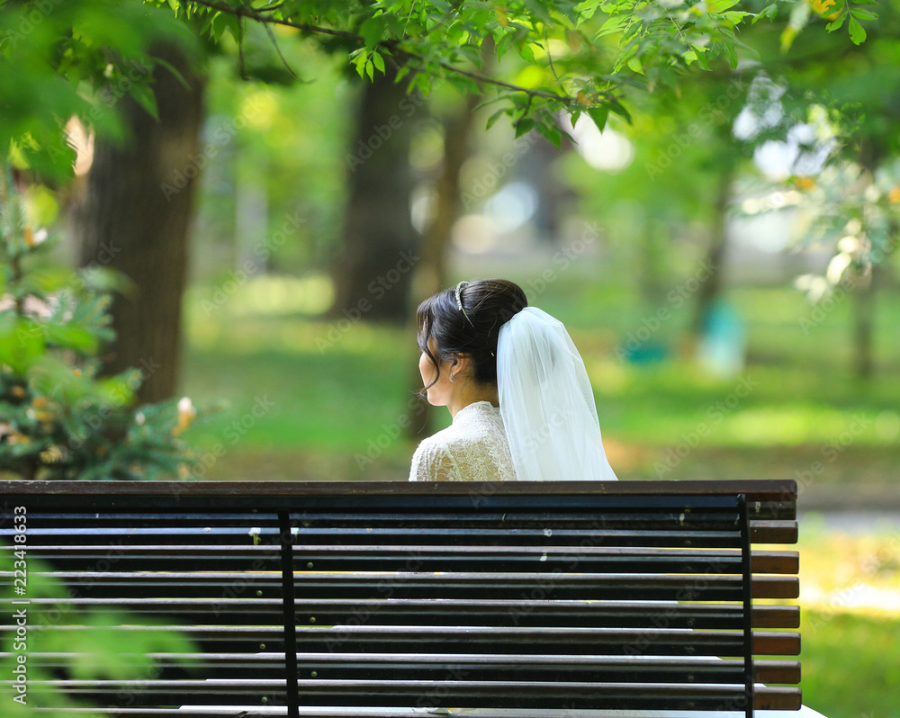 Fototapeta premium the bride sits alone on a bench in the park