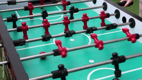 Playing foosball table game, close up view at green field with rotating player figures photo