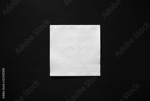 Blank white paper napkin on black background with copy space. Flat lay.