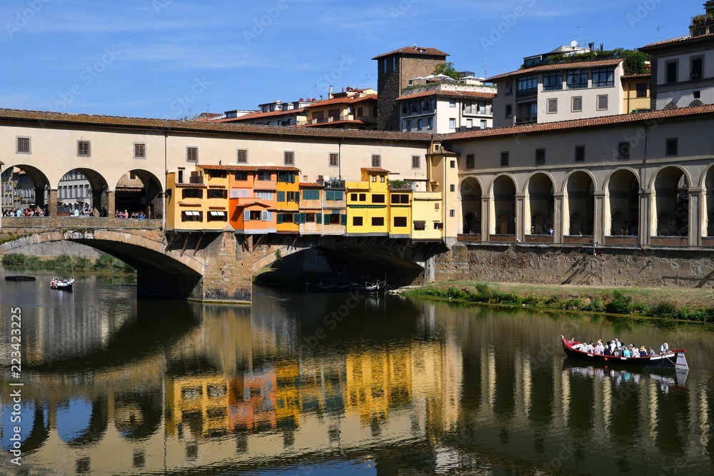 Tourists on the boat under the Ponte Vecchio in Florence reflecting on the waters of the river Arno. Italy.