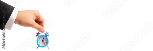 Obraz na plátně A businessman's hand holds a blue alarm clock on a white background