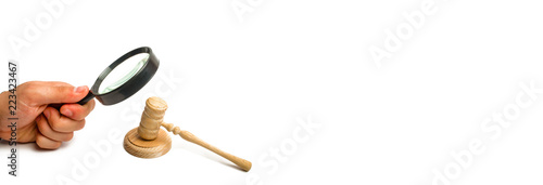 The hand with the magnifying glass gazes intently at the hammer of the judge. The concept of investigation of court cases. Corruption in the courts. Arbitrage practice. Appeal for sentencing.