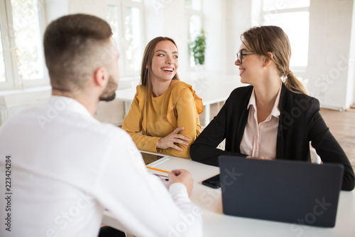 Two joyful business women happily looking at each other while spending job interview in modern office