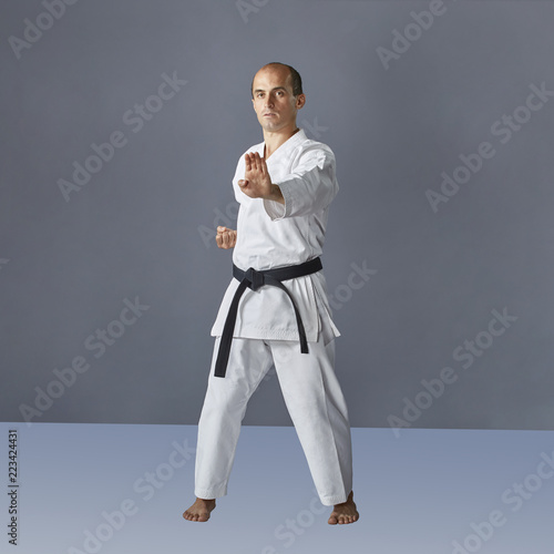 Formal exercises karate adult athlete performs on a dark gray background