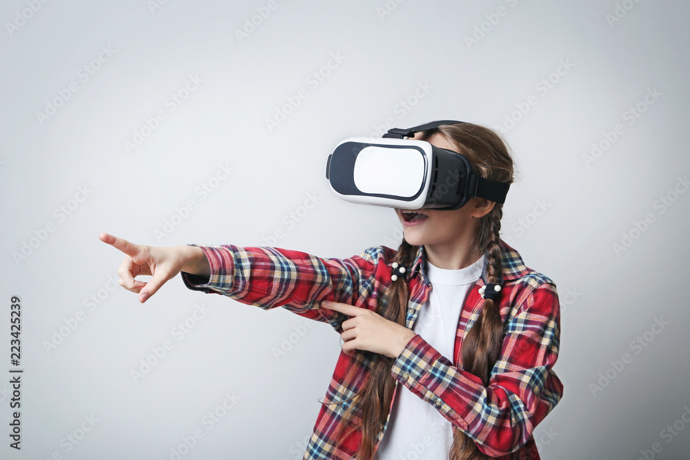 Young girl in virtual reality goggles on grey background Young girl in virtual reality goggles on grey background