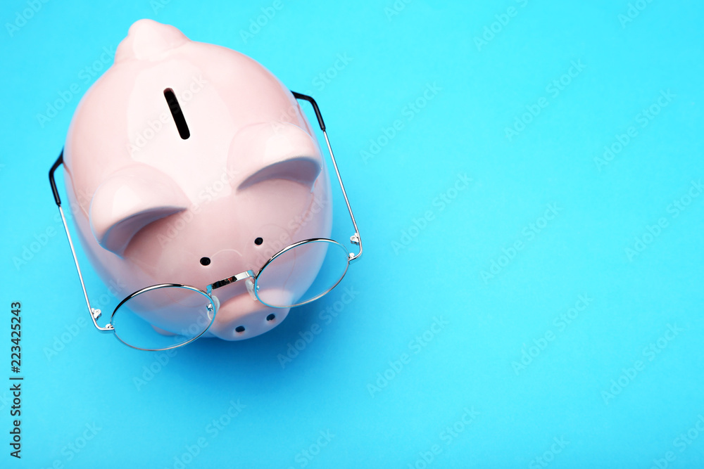 Pink piggy bank with glasses on blue background Pink piggy bank with glasses on blue background