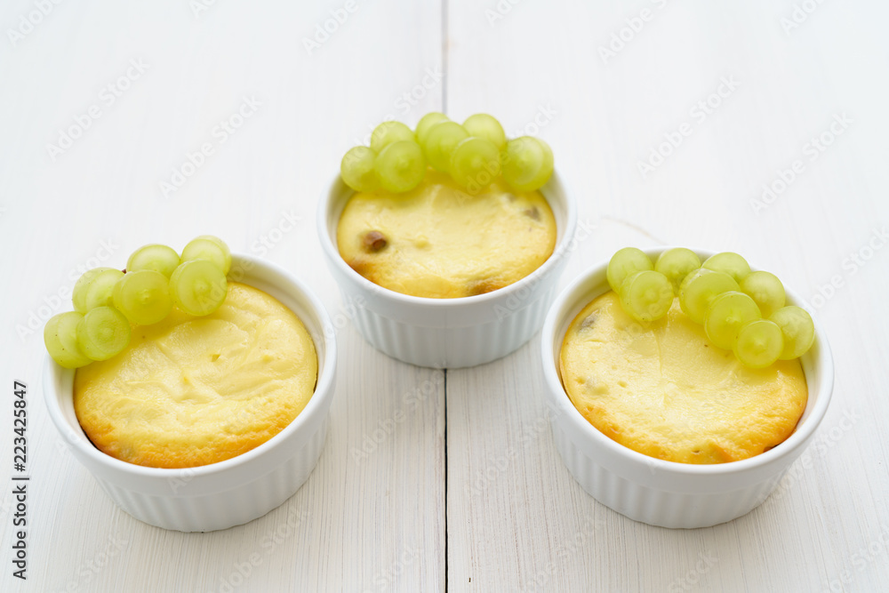 Mini zapekankas (baked quark dessert) with raisins and fresh grape. White wooden table, high resolution