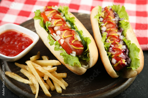Hot dogs with vegetables and french fries on wooden table