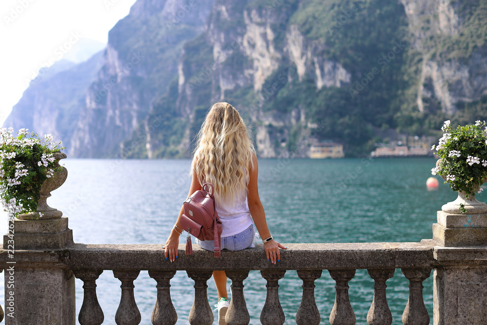 Bella ragazza giovane sta guardando bel paesaggio  al Lago di Garda  Foto fato a Riva del Garda, Italia.  Beautiful young girl is looking at beautiful landscape at Lake Garda. Riva del Garda, Italy.