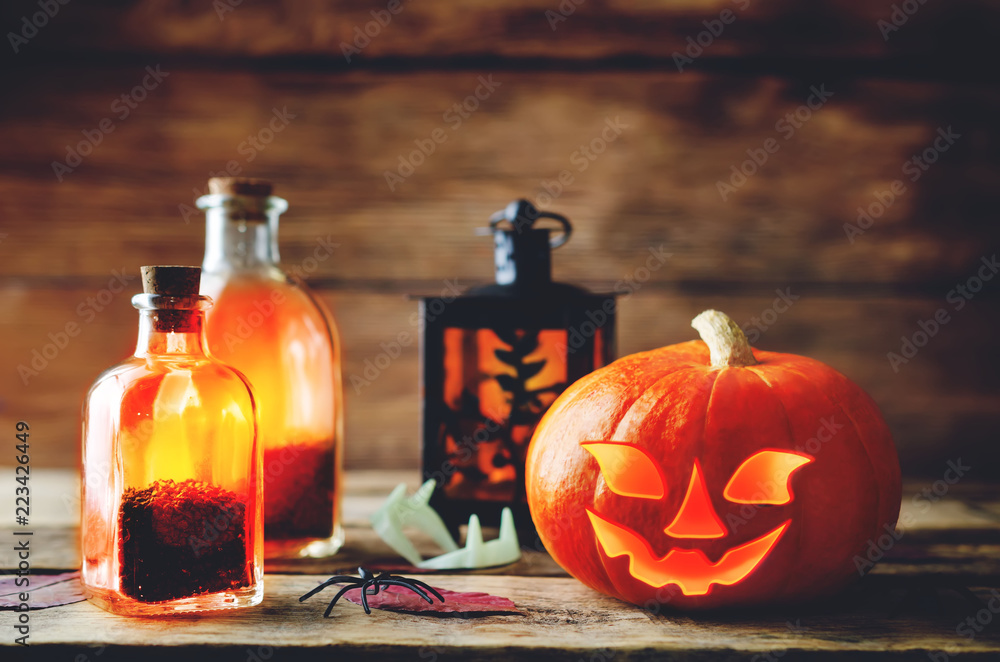 Glowing pumpkin with jars on dark wood background. Halloween concept. Glowing pumpkin with jars on dark wood background. Halloween concept.