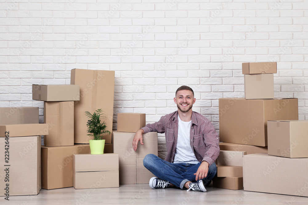 Young man with cardboard boxes on brick wall background Young man with cardboard boxes on brick wall background