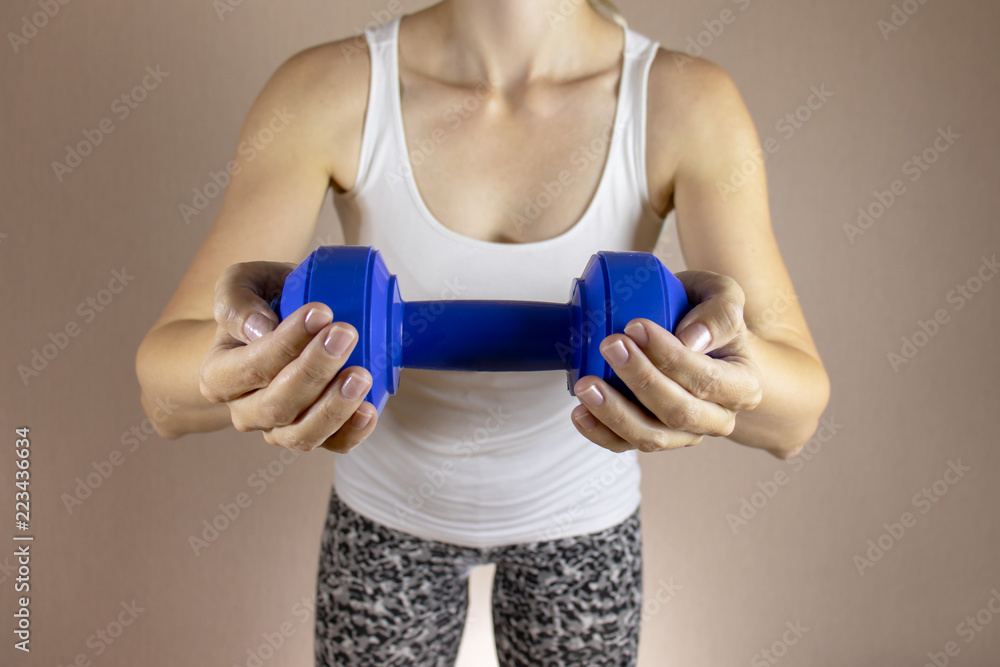 Cropped woman in white shirt with dambbell in her hands clase up. Slimming diet and fitness concept
