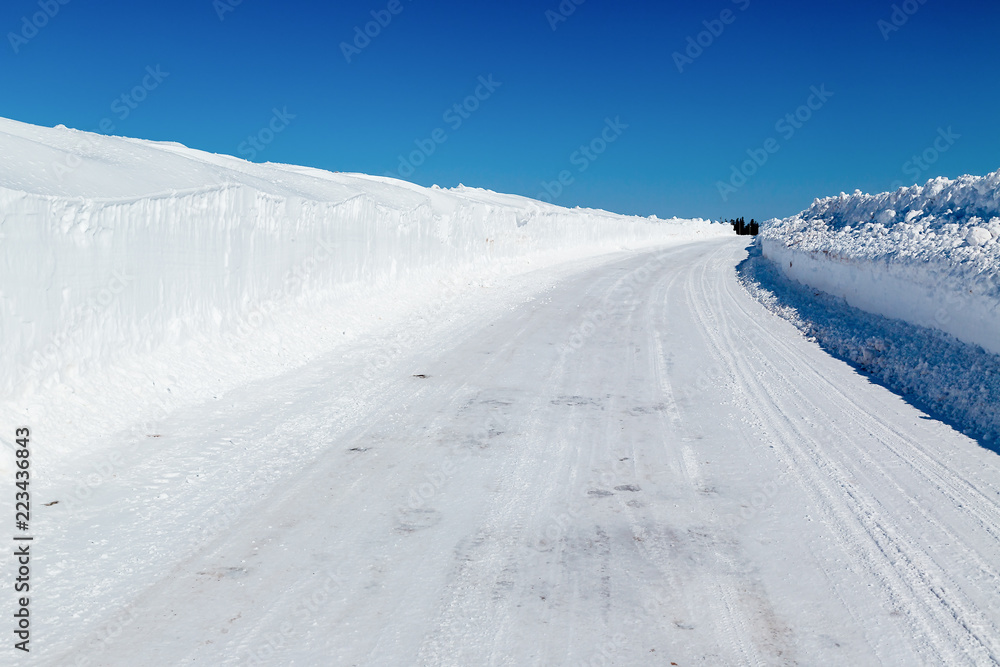 Winter road with tall snowbanks on each side. Winter road with tall snowbanks on each side.
