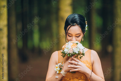 Photography Portrait of a beautiful bridesmaid posing with bride's wedding bouquet in pine forest