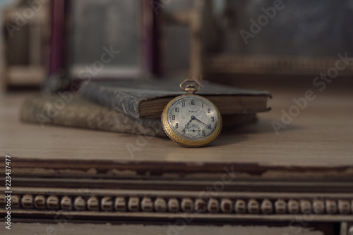 Old antique pocket watch leaning on antique books