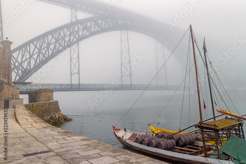 Boot mit Portweinfässern am Pier von Porto mit der Brücke Dom Luis I im Nebel photo