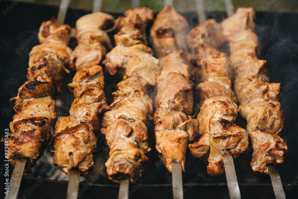 Appetizing shish kebab roasted on skewers on open air charcoal grill. Shish kebab with smoke